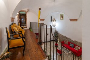 Un couloir avec un plancher en bois, un canapé rouge et un fauteuil jaune.