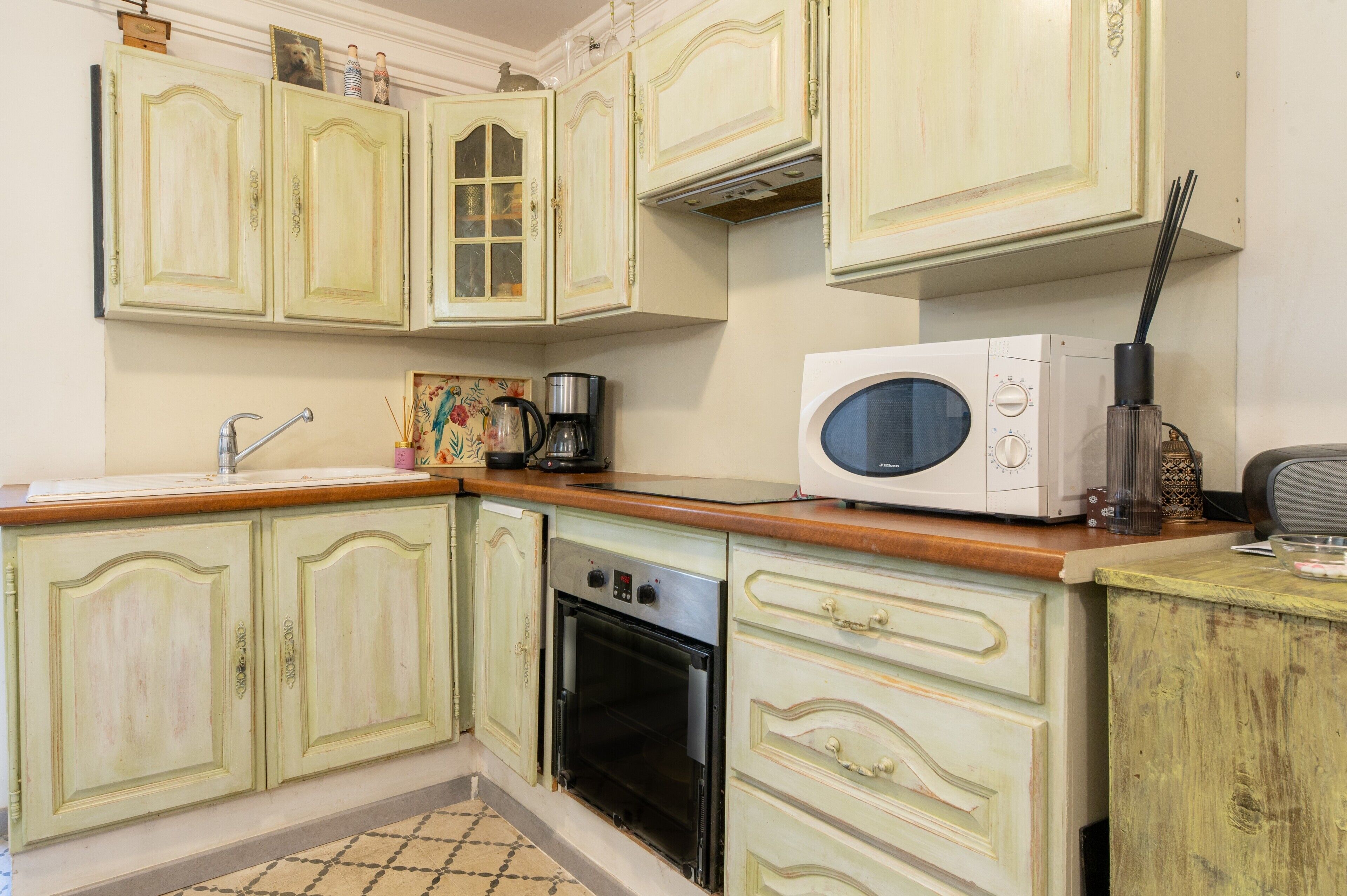 A kitchen with vintage-style cabinets, a coffee maker, and a microwave.