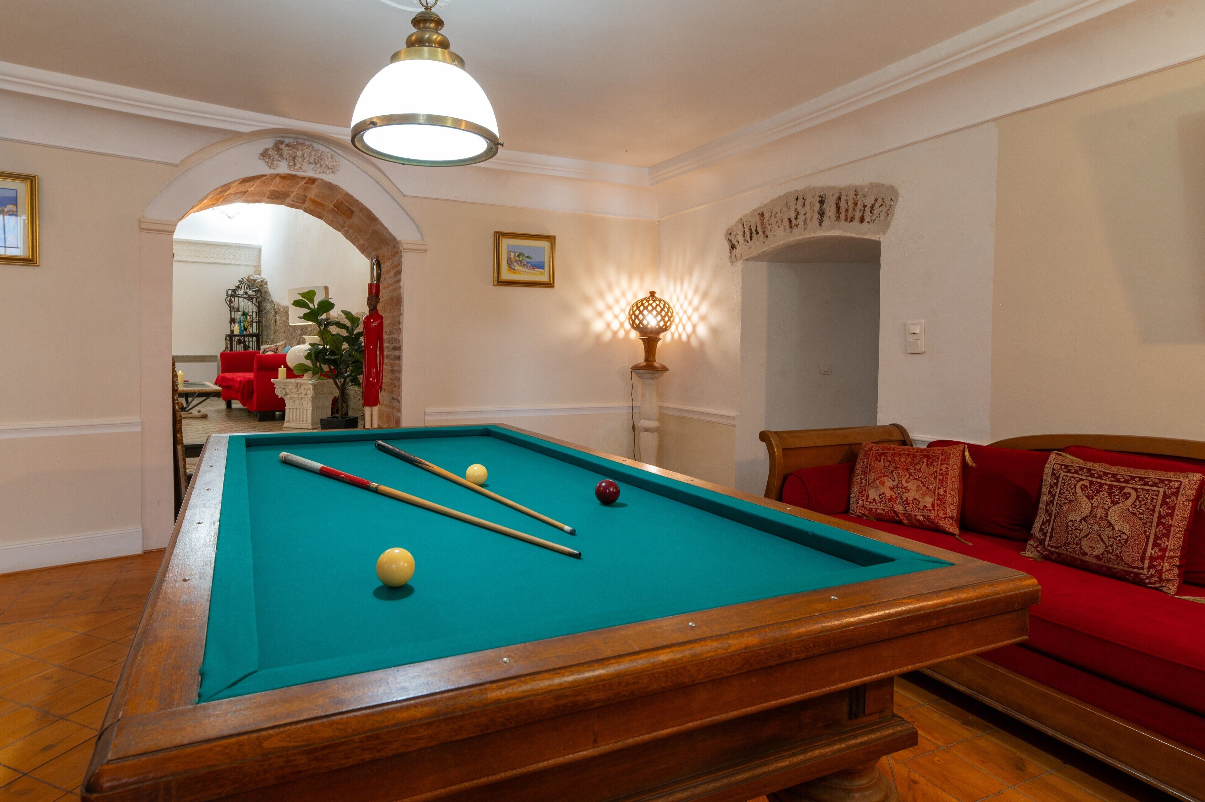 A pool table with balls, a red sofa, and a lamp.