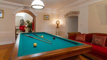 A pool table with balls, a red sofa, and a lamp.