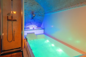 A spa room with a bathtub, a shower, and a stone wall. - 150 m² in a Former 16th-Century Defense Tower (Bastia)