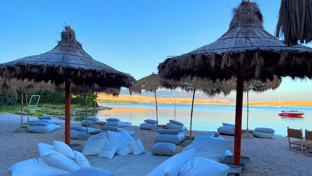 A beach with thatched umbrellas, lounge chairs, and pillows. - Apartment Top 5 with sunny balcony and sea view (Novalja)