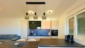 A modern kitchen with a marble countertop, built-in appliances, and pendant lighting. - Apartment Top 5 with sunny balcony and sea view (Novalja)