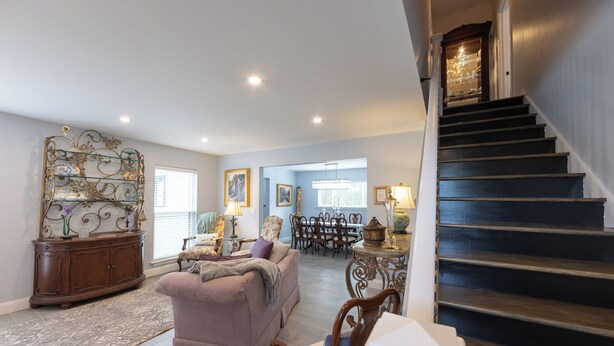 Un vaste salon comprenant un escalier, un coin repas et une pièce décorative en métal accrochée au mur.