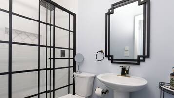 Een badkamer met toilet, wastafel, spiegel en douchecabine.