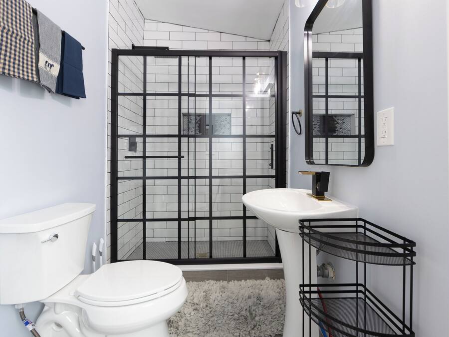 A bathroom with a toilet, sink, shower enclosure, and a mirror.