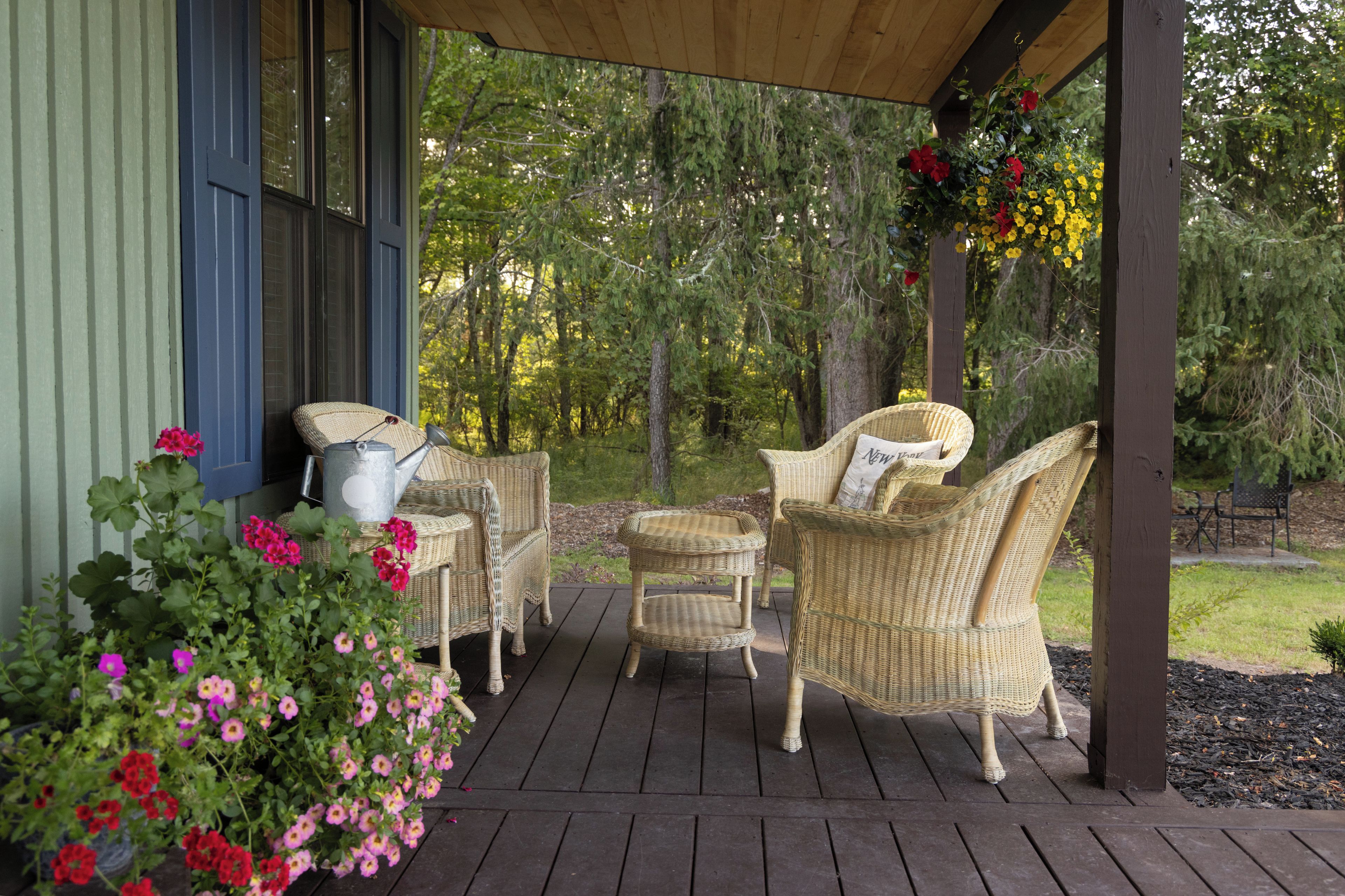 A covered outdoor seating area with wicker furniture and a garden view.