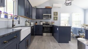 Une cuisine moderne avec des meubles de couleur sombre, un four à micro-ondes en acier inoxydable et un four traditionnel.