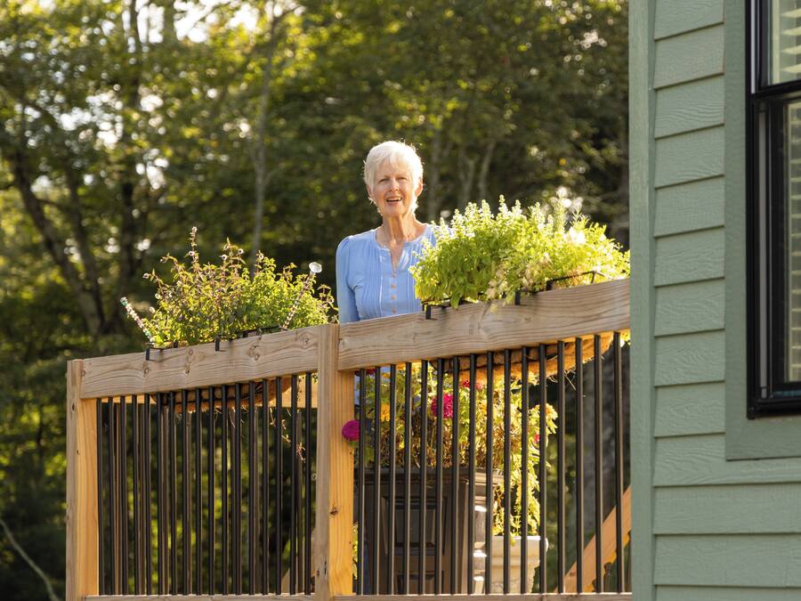 A wooden balcony with plants and a window.
