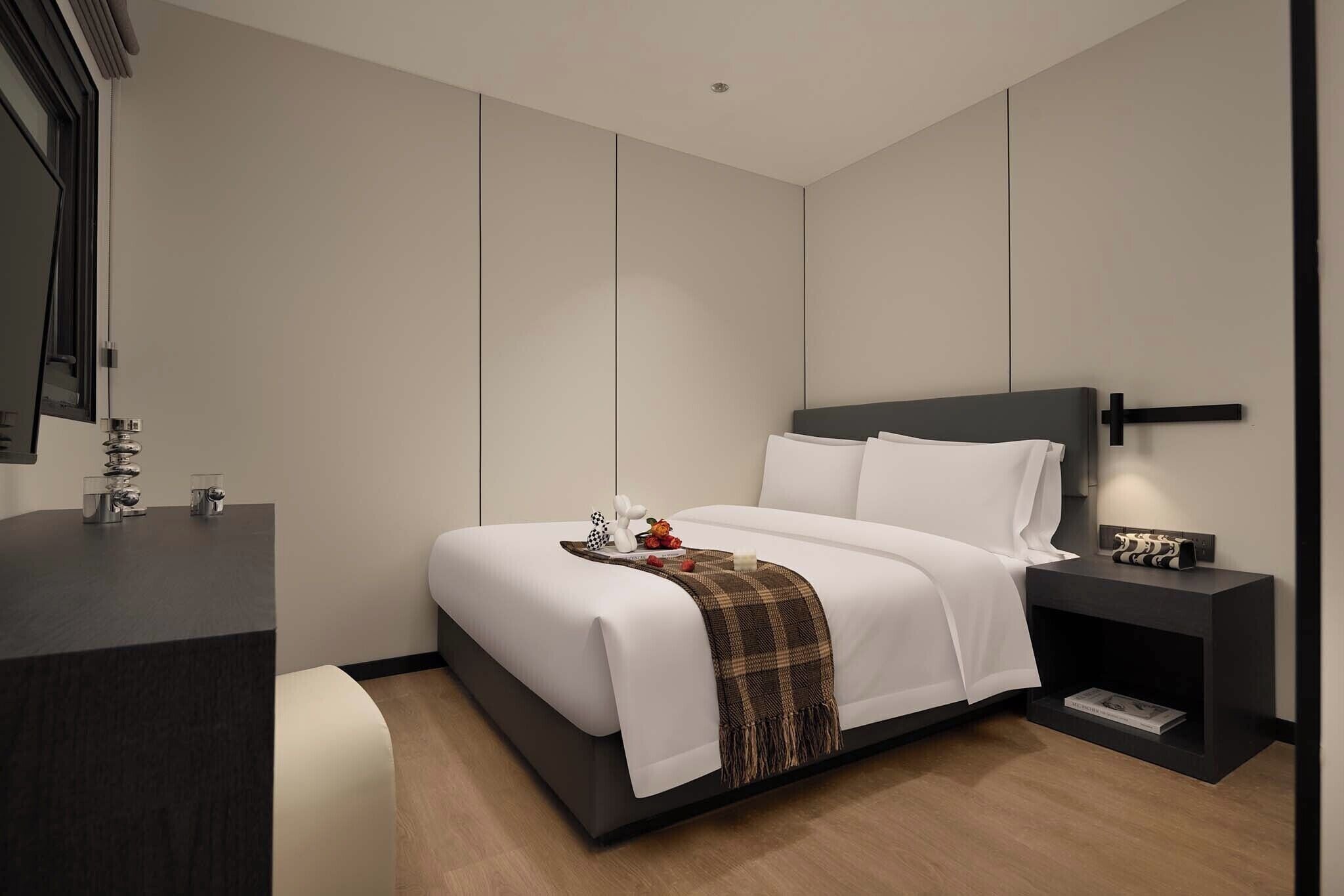 A modern bedroom with a large bed, a bedside table, a nightstand, and a mirror.