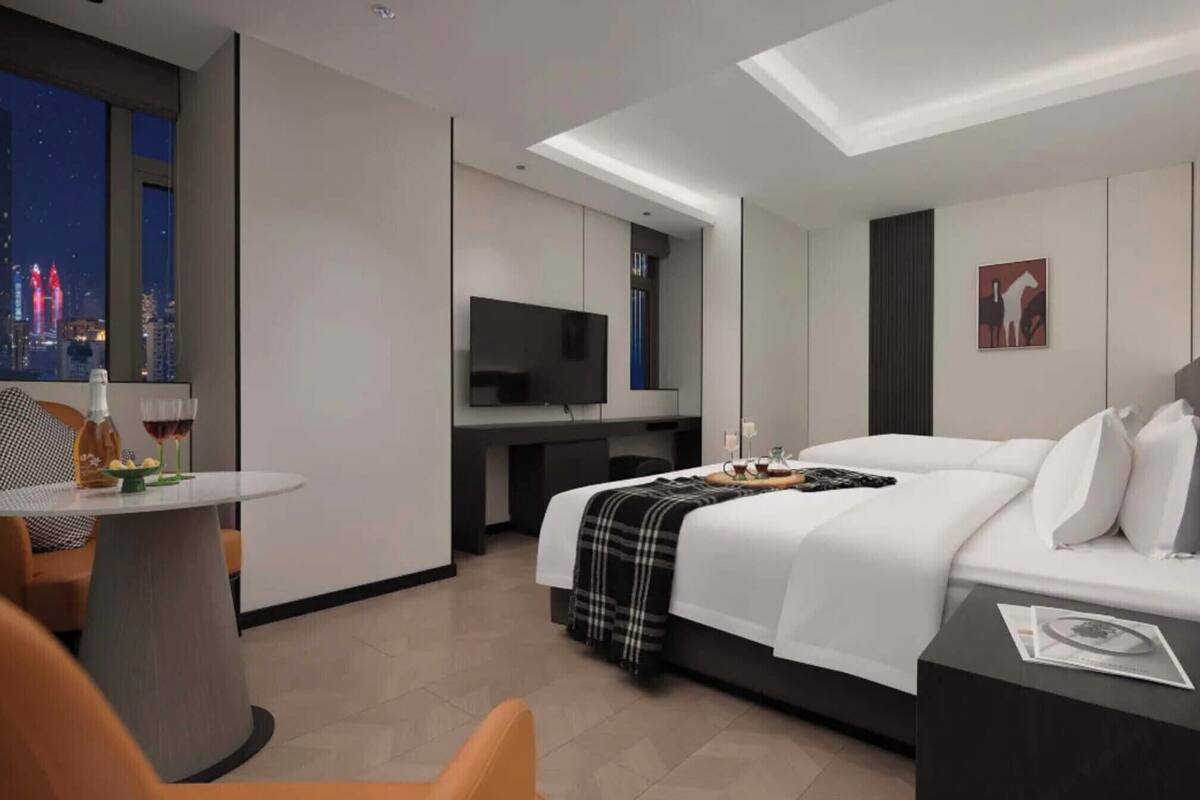Ein modernes Hotelzimmer mit Bett, Schreibtisch, Fernseher und Blick auf die Stadt.