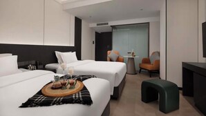Een moderne hotelkamer met twee bedden, een zithoekje en een televisie.