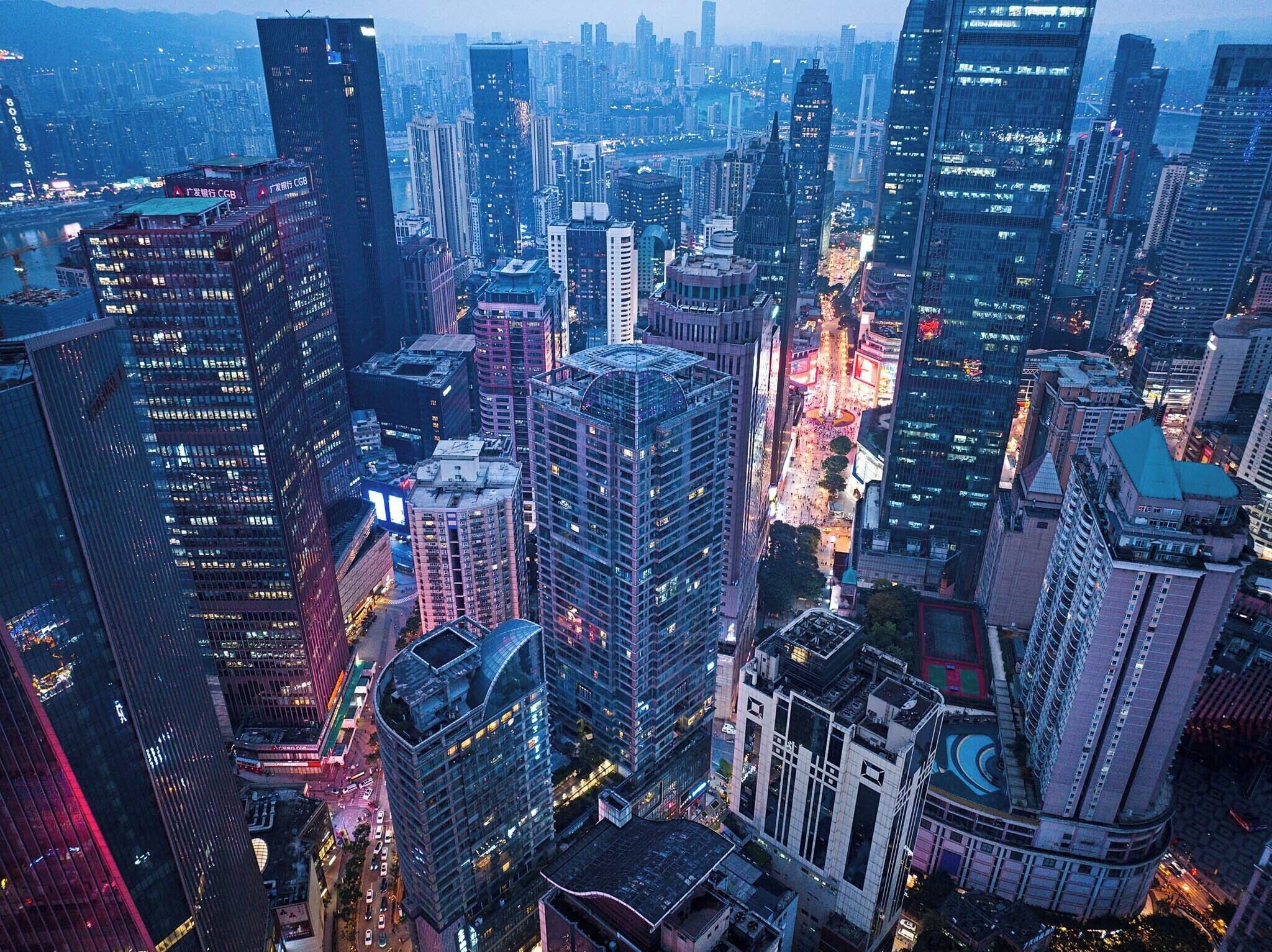 A dense urban skyline with high-rise buildings, a central roundabout, and a river.