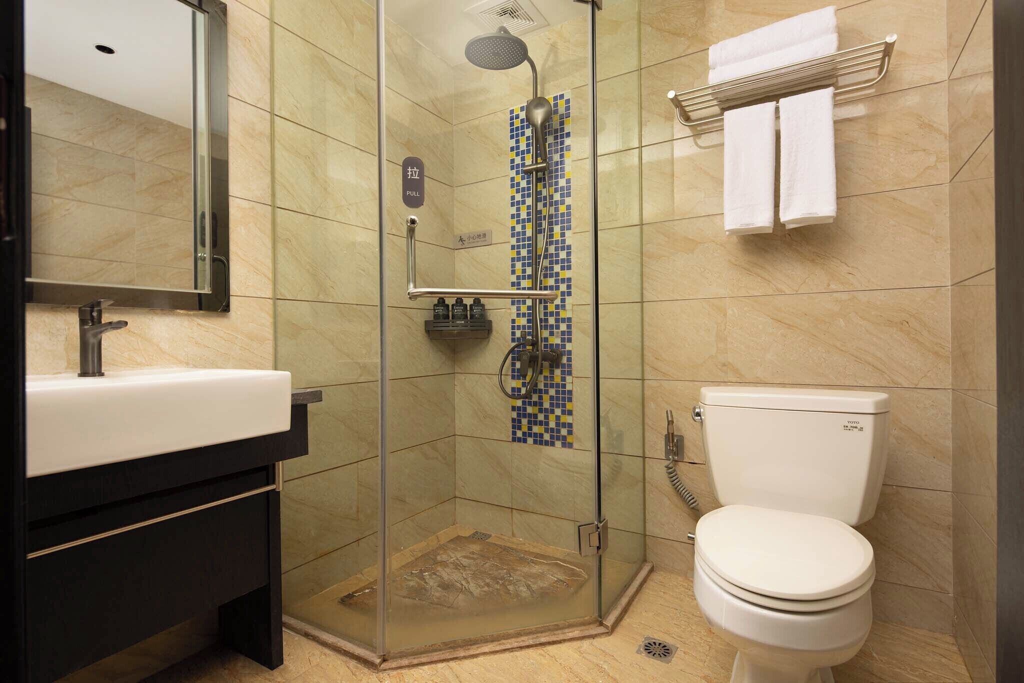 Een moderne badkamer met een douchecabine van glas, een wit toilet en een zwarte wastafel met spiegel.