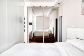 A modern hotel room with a bed, bedside tables, a lamp, and a sliding door leading to another room. - Hostmate - Milano - Viale Monza - NoLo (Milano)
