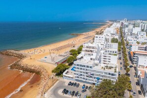 An aerial view of a coastal city with a beach, buildings, and a clear sky. - Horizon Smiles Beach Apartments (Loulé)