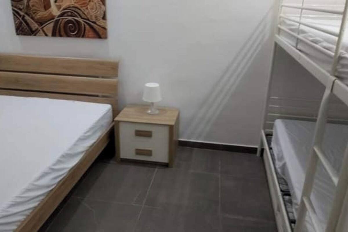 Ein Schlafzimmer mit einem hölzernen Bett, einem Nachttisch mit Lampe sowie einem Stockbett.