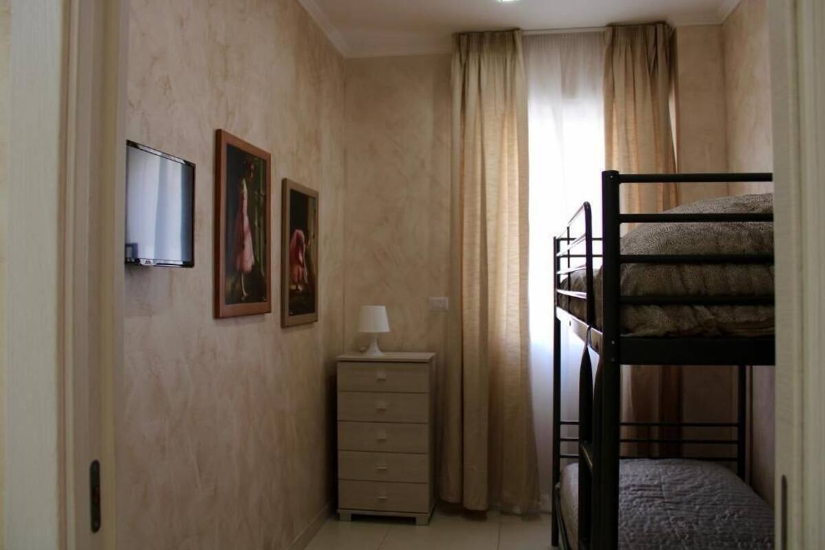Ein Zimmer mit Etagenbett, Fernseher, Kommode und zwei gerahmten Bildern an der Wand.