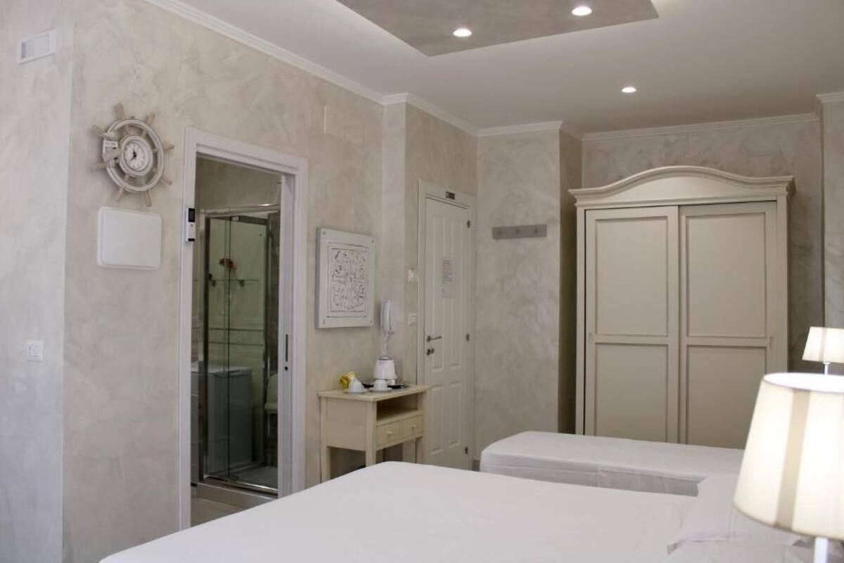 Ein Hotelzimmer mit Bett, Schreibtisch mit Lampe, Kleiderschrank und Duschbereich.