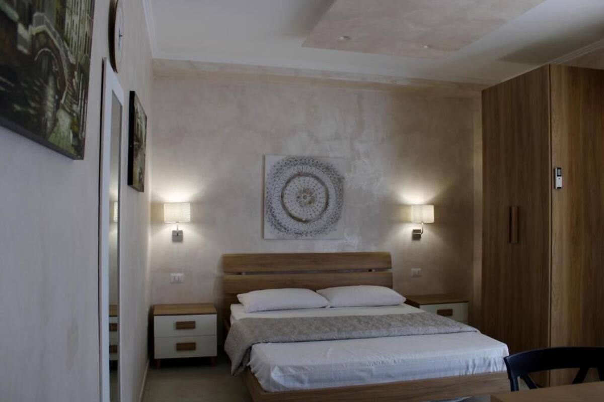 Ein Schlafzimmer mit einem hölzernen Bett, Nachttischlampen, einer Wanduhr und einem Holzschrank.