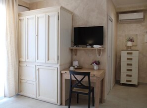 Una habitación con escritorio, silla, televisor y un armario.
