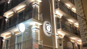 A multi-story building with balconies, a circular sign, and a street lamp. - MEDUSA Residence B&B  (Margherita di Savoia)
