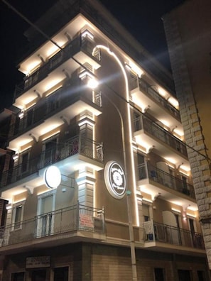 A multi-story building with balconies, a circular sign, and a street lamp. - MEDUSA Residence B&B  (Margherita di Savoia)