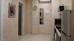 A narrow hallway with a door, a clock, an air conditioning unit, and a refrigerator. - MEDUSA Residence B&B  (Margherita di Savoia)