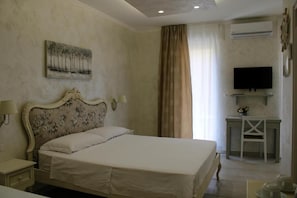 A hotel room with a bed, a desk, a television, and a painting on the wall. - MEDUSA Residence B&B  (MARGHERITA DI SAVOIA)