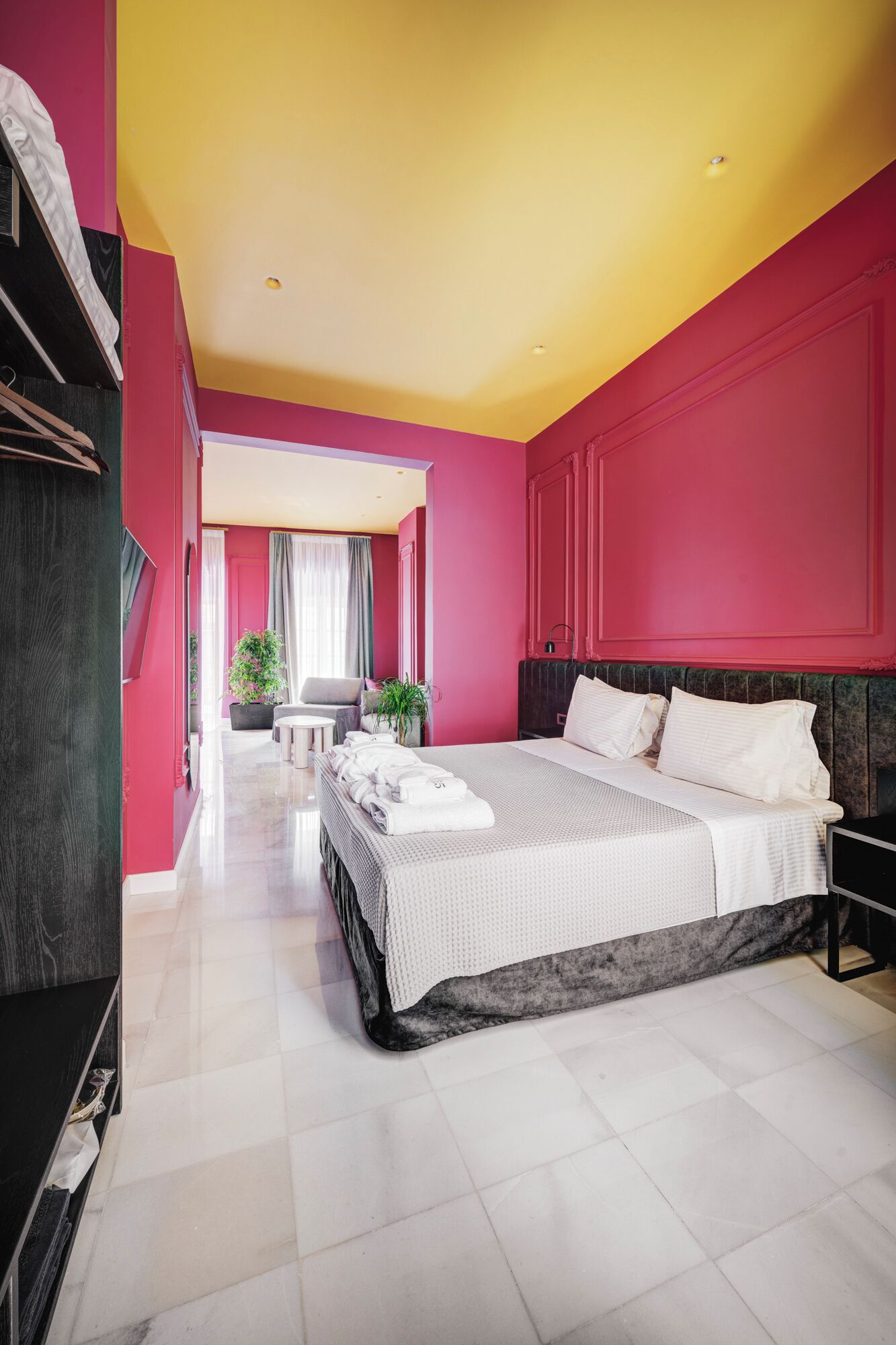 A modern hotel room with a large bed, a desk, and a seating area.