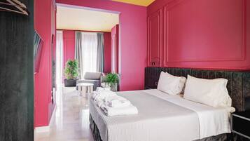 A modern hotel room with a large bed, a desk, and a seating area.