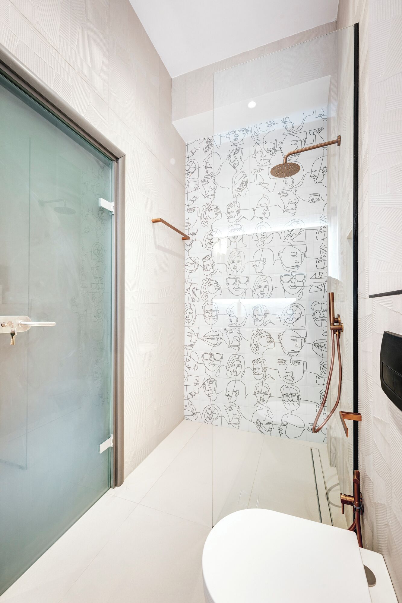 Ein modernes Badezimmer mit Glastür, einer Dusche mit Musterfliesen und einer weißen Toilette.