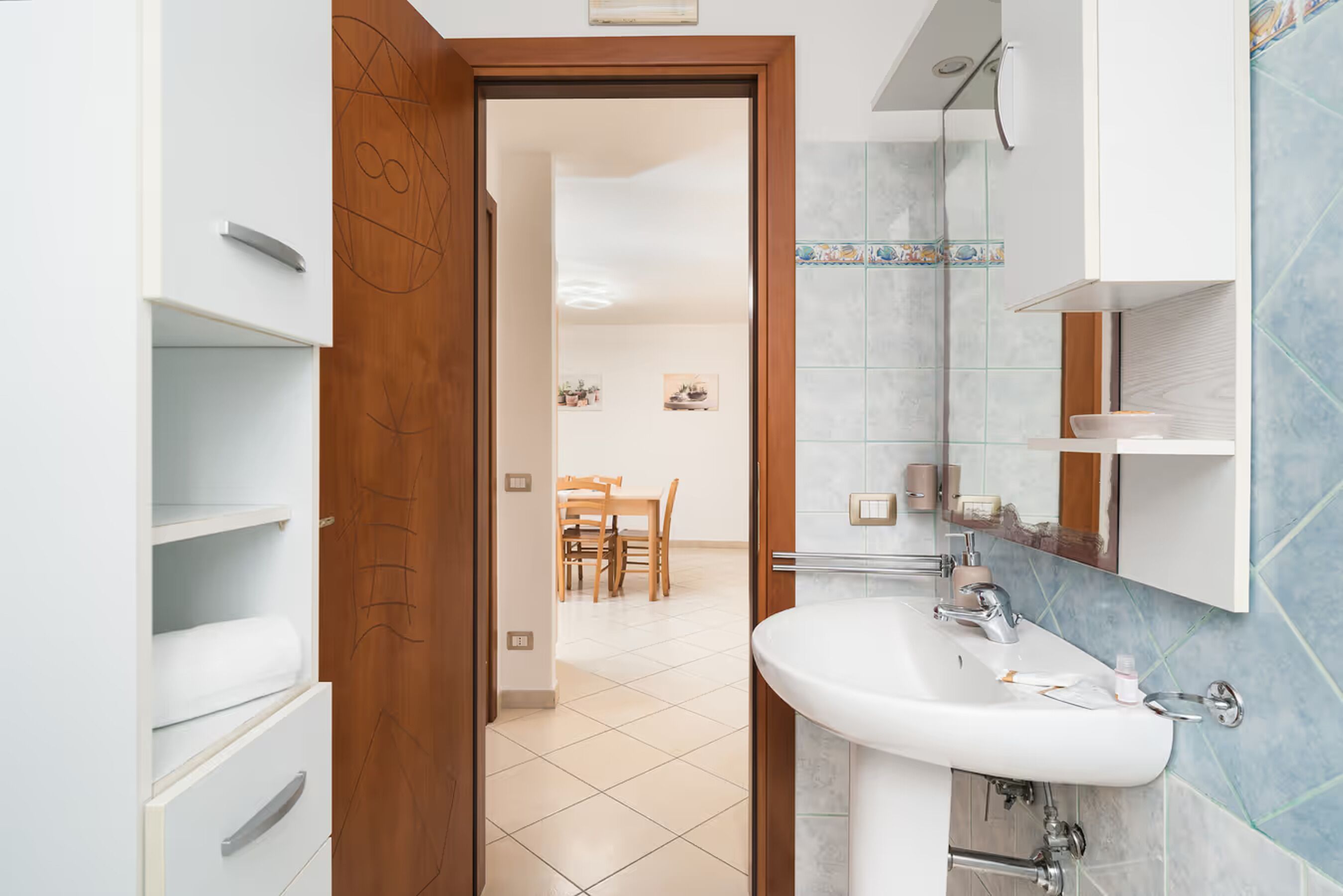 A bathroom with a sink, mirror, and tiled walls.