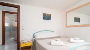 Ein Hotelzimmer mit einem Bett, einem Nachttisch, einem Spiegel und Kunstwerken an den Wänden.