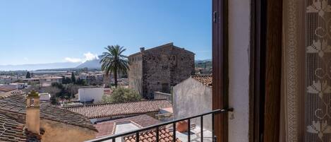 A balcony with a view of a town, a palm tree, and a mountain.