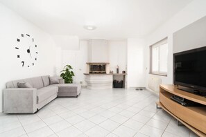 Een moderne woonkamer met een hoekbank, een flatscreen televisie, een open haard en een groot raam.