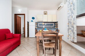 Ein kompakter Wohnbereich mit Essplatz, Küchenzeile und einem roten Sofa.