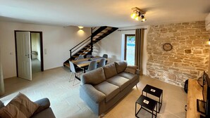 Ein Wohnzimmer mit einer Couch, einem Esstisch und einer Treppe.