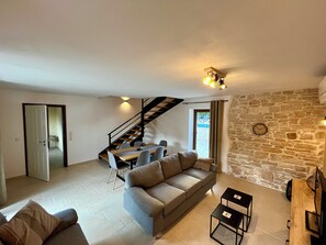 Ein Wohnzimmer mit einer Couch, einem Esstisch und einer Treppe.