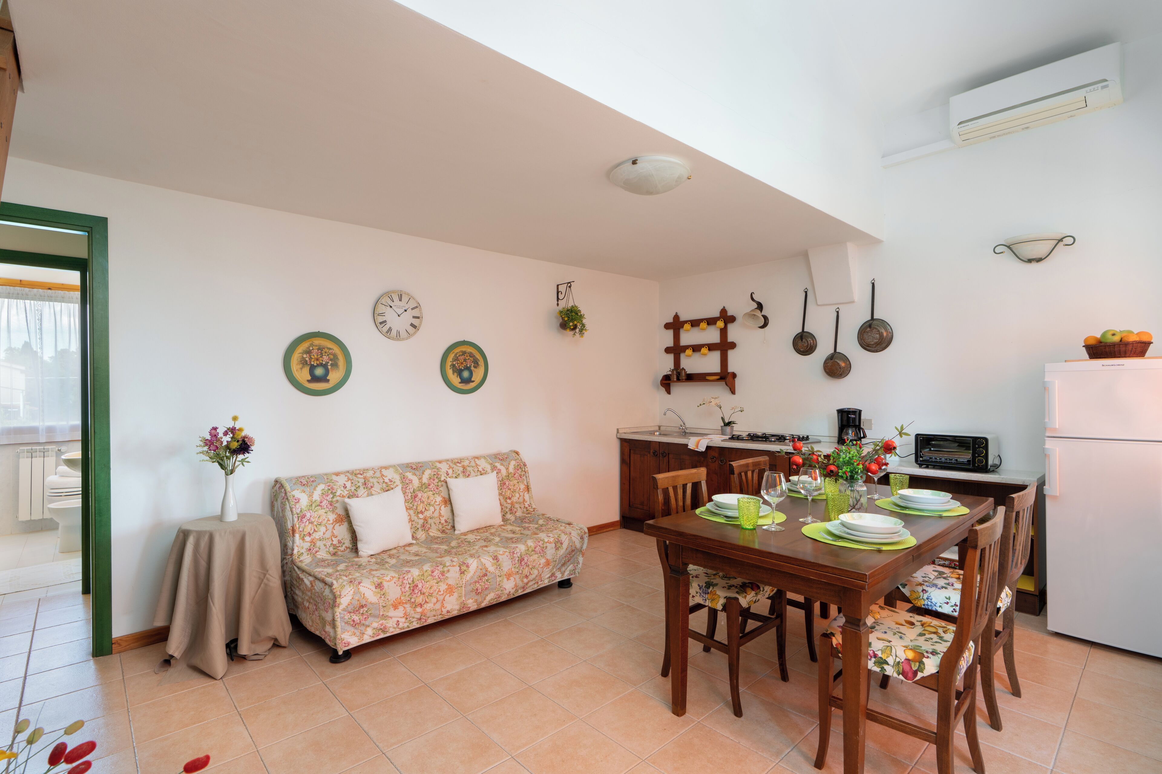 A cozy living room with a sofa, dining table, and kitchen area.