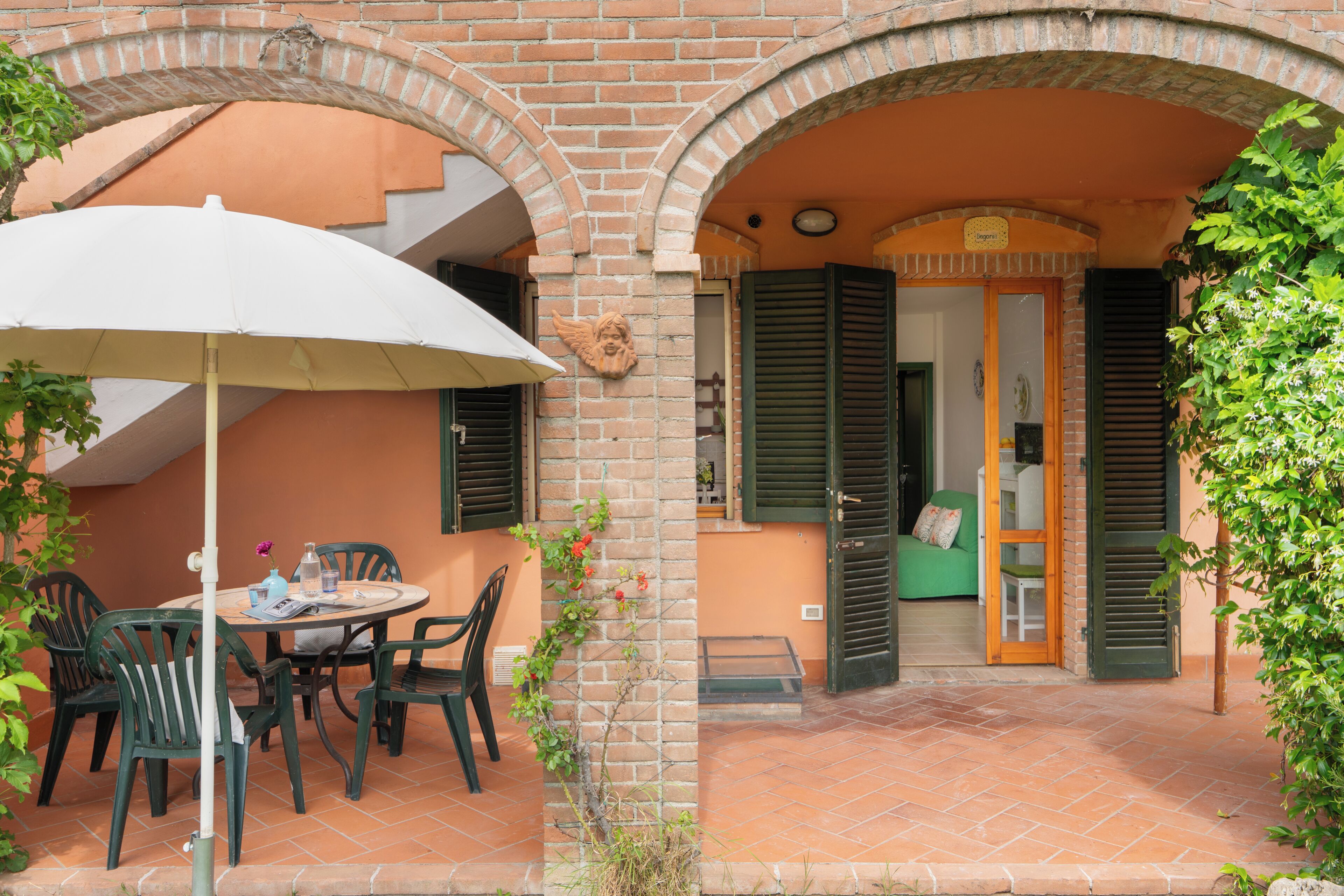 Un patio al aire libre con una mesa, sillas, una sombrilla y un arco de ladrillo.