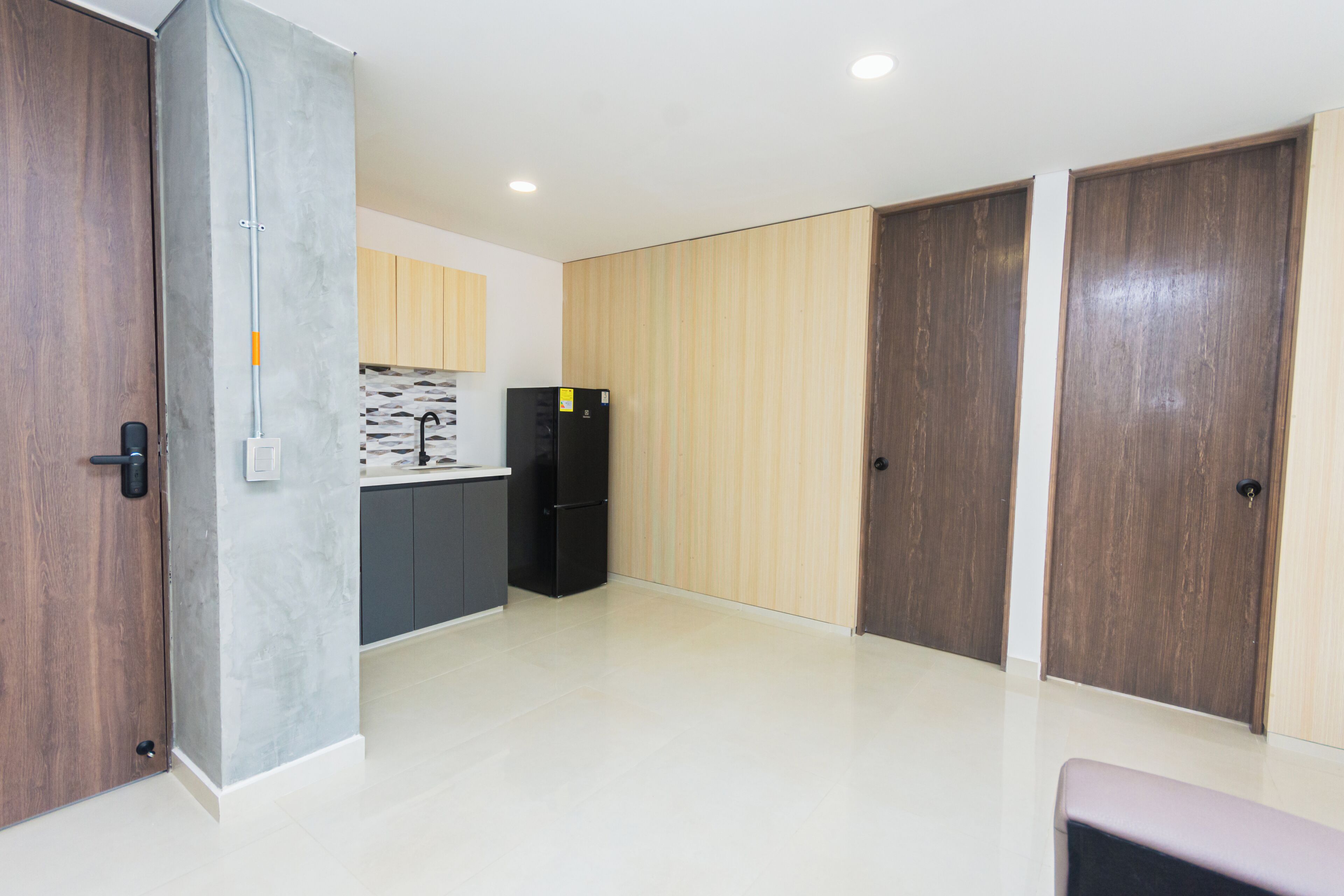 A modern kitchen with a black refrigerator, wooden cabinets, and a tiled backsplash.