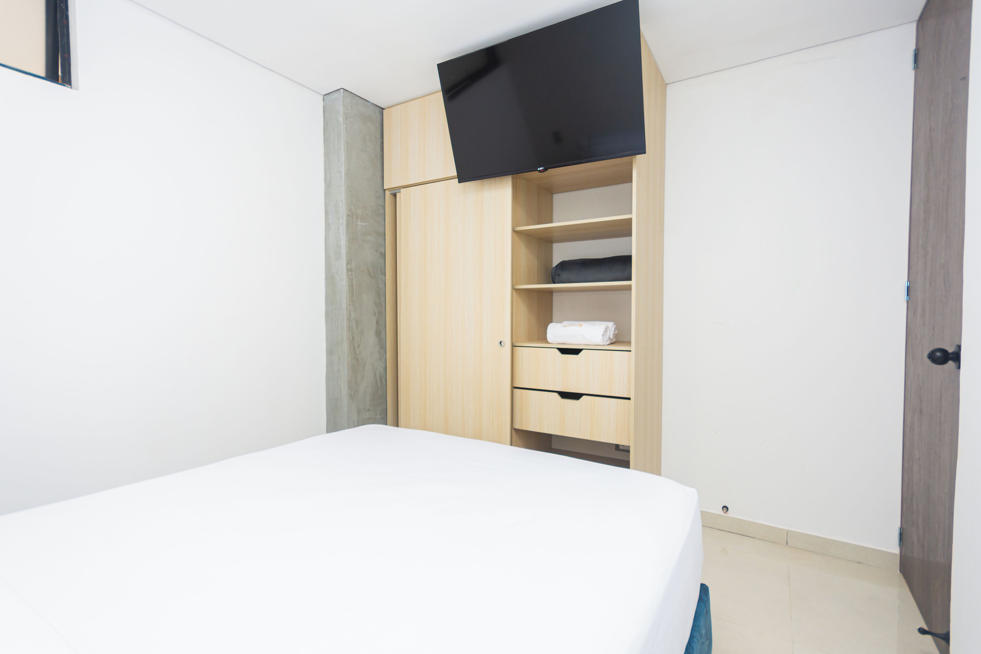 Une chambre à coucher comprenant un lit, une armoire et un téléviseur à écran plat fixé au mur.