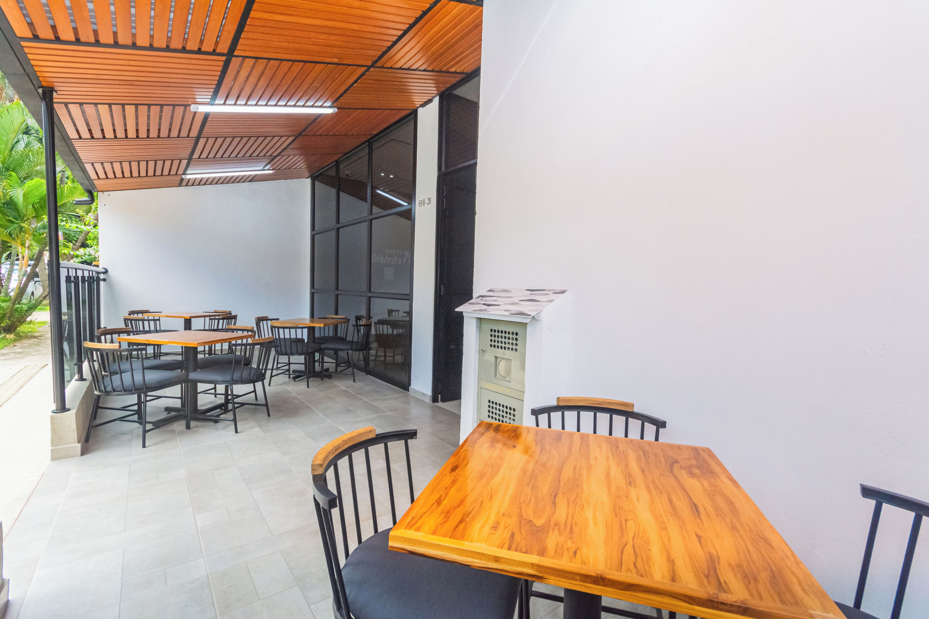 A cafe with wooden tables and chairs, a tiled floor, and a modern ceiling design.