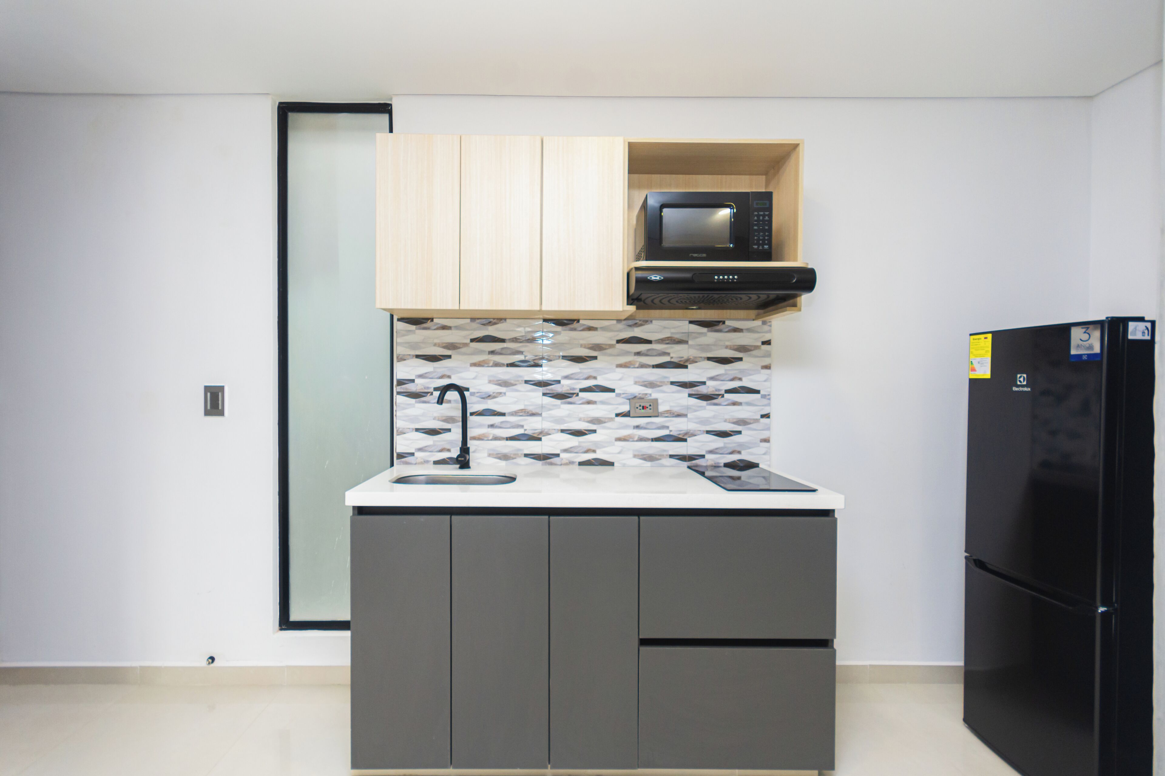A compact kitchen with a microwave, a refrigerator, and a sink.