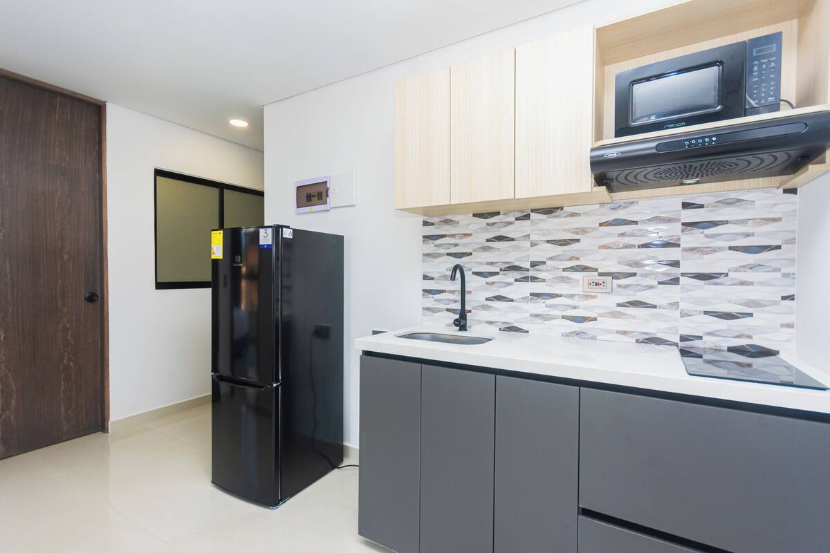 Una cocina moderna con un refrigerador negro, un microondas y un salpicadero de azulejos.