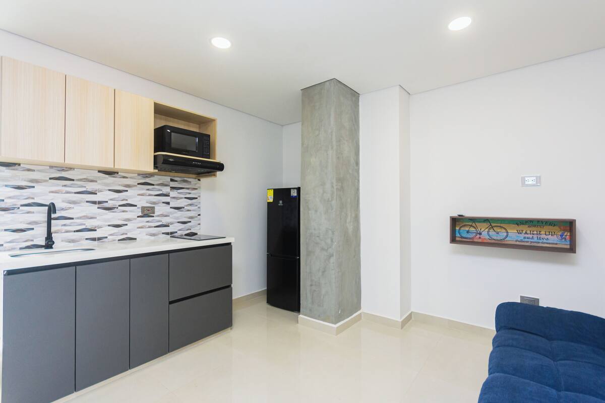 Una cocina moderna con microondas, refrigerador y salpicadero de azulejos.