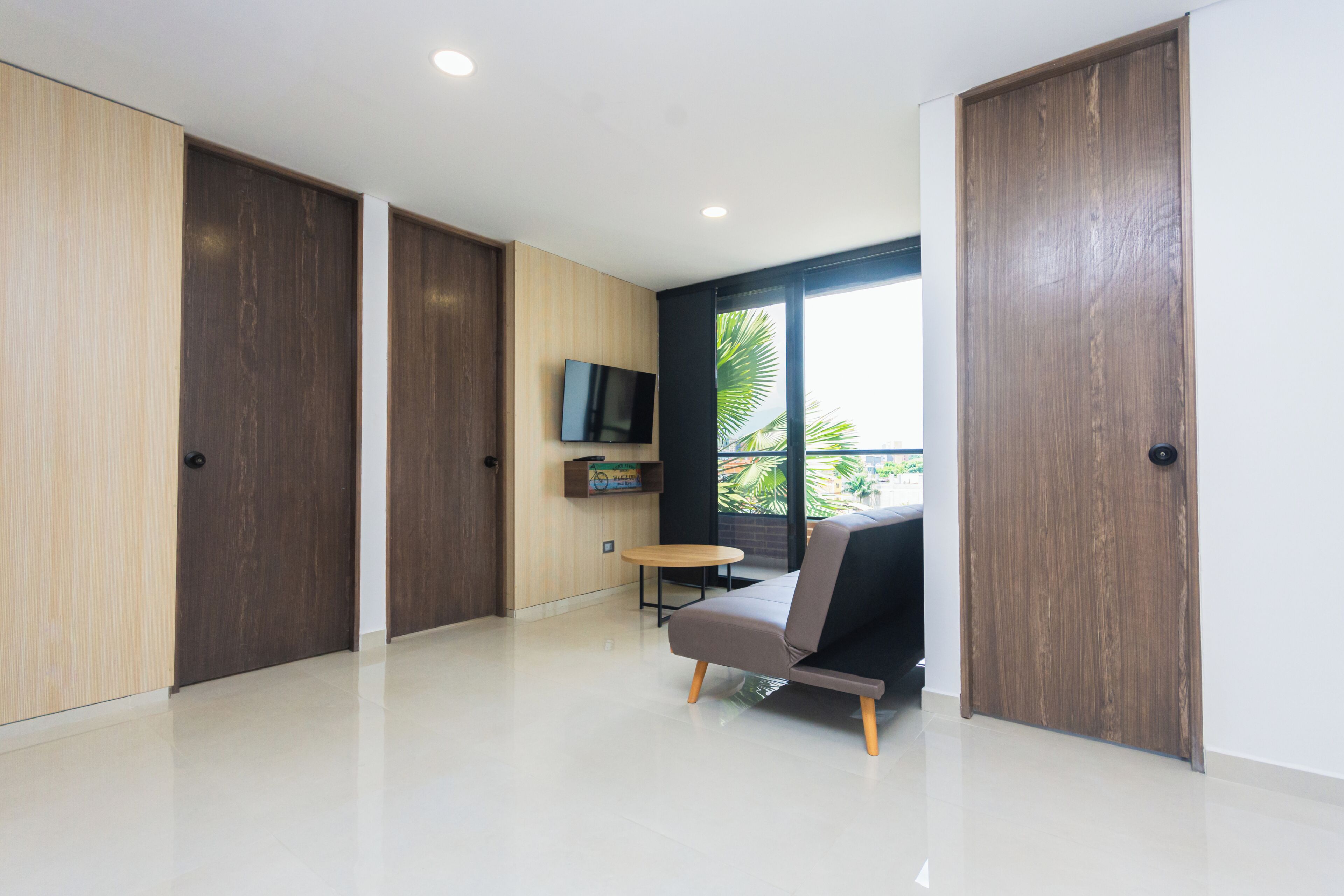 A modern room with a sofa, a TV, and a window with a view.