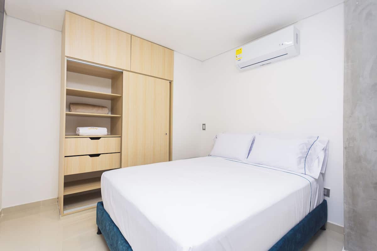 Un dormitorio con cama, armario y aire acondicionado.