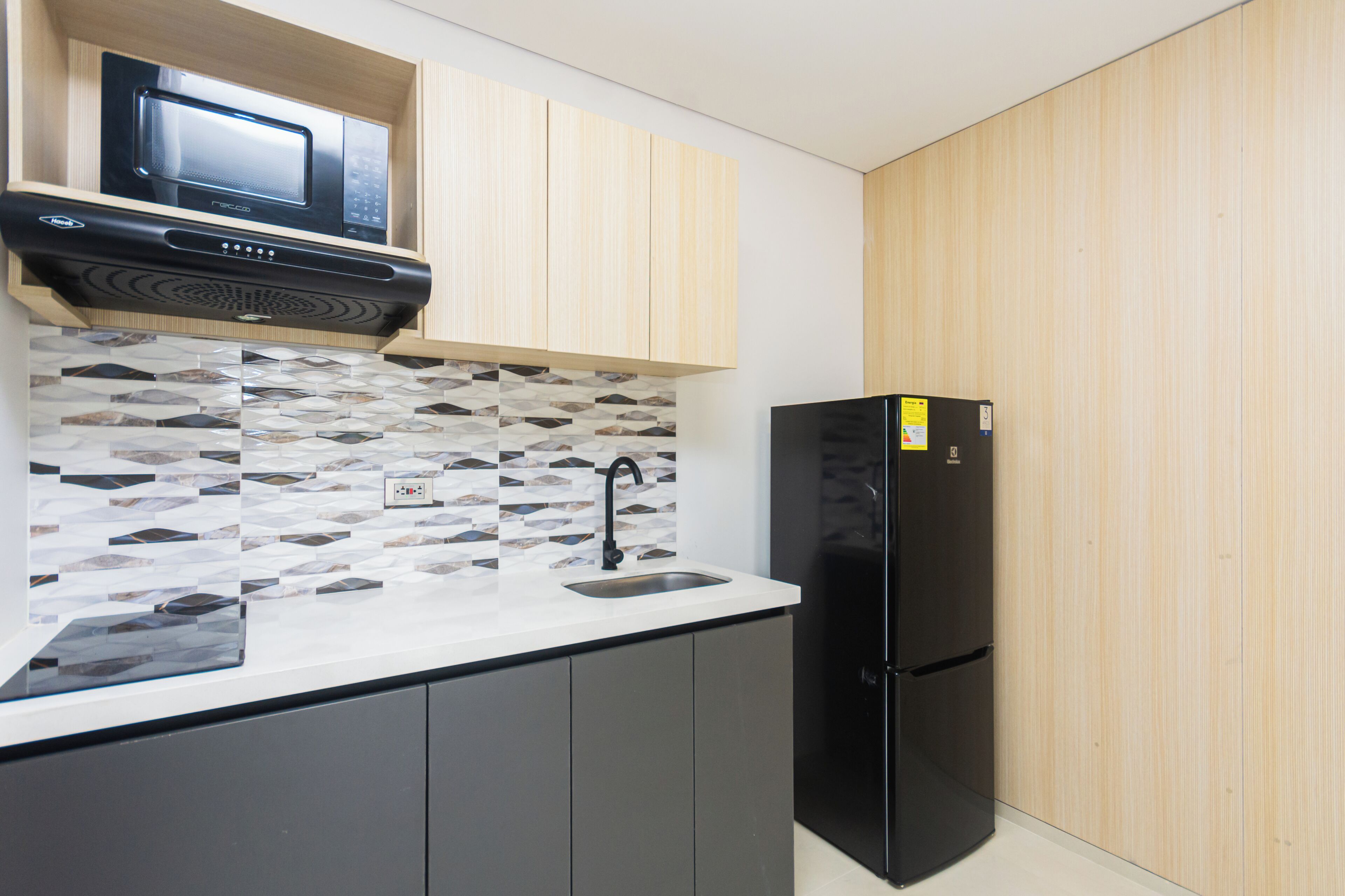 A kitchen with a microwave, sink, and black refrigerator.